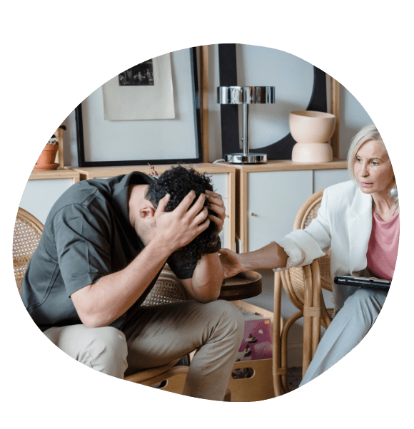 man with his head in his hands being consoled by therapist
