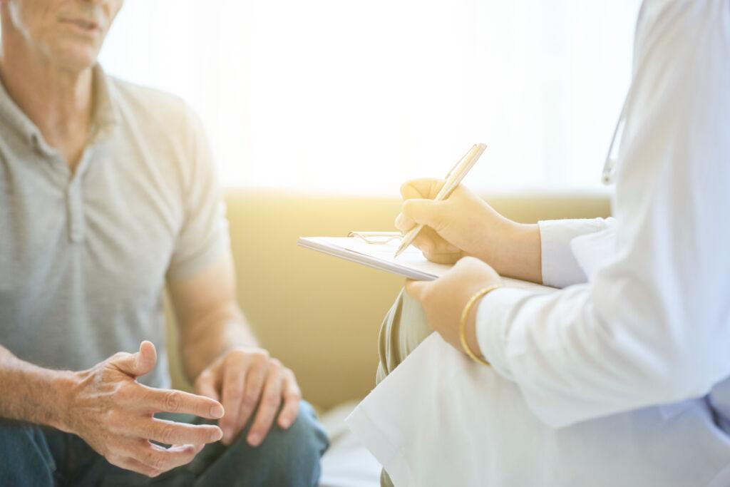 Healthcare professional taking notes while speaking with a patient during a memory screening.